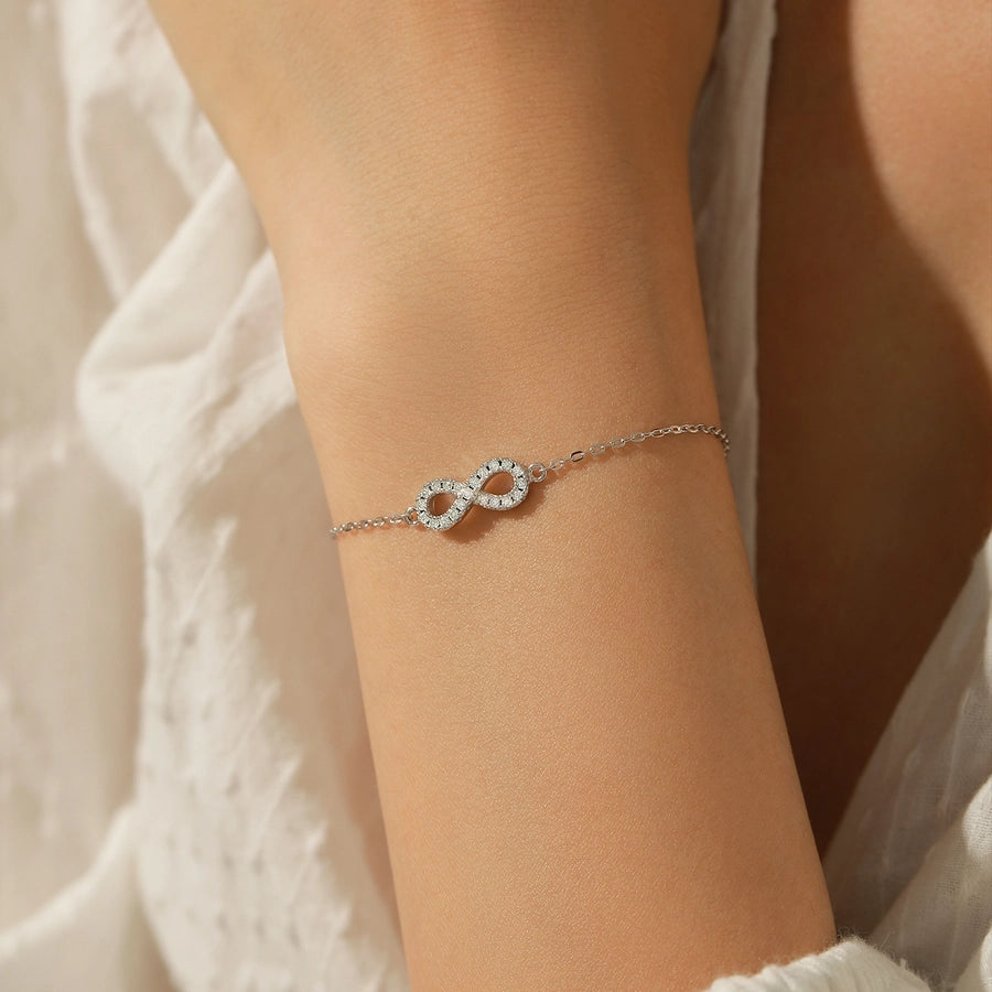 Infinity bracelet: sterling silver band adorned with moissanite diamonds.